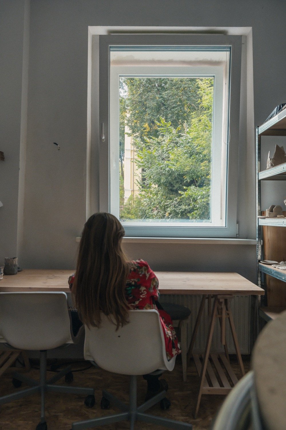 Moteris sėdi prie studijos lango darbo zonoje